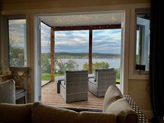 two wicker chairs sitting on top of a wooden deck next to an open door