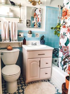 a white toilet sitting next to a bath tub in a bathroom with blue tile on the walls