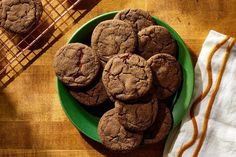 a green plate filled with chocolate cookies on top of a wooden table