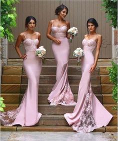 three bridesmaids in pink dresses standing on steps with bouquets and greenery