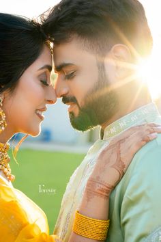 a man and woman standing next to each other in front of the sun with their faces close together