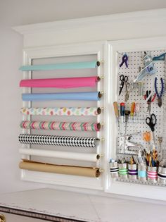 an organized craft room with scissors, tape and other items on the wall behind it