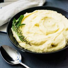 mashed potatoes in a black bowl with herbs on top