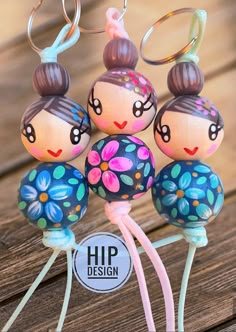 three little dolls are hanging from the handles of some kind of keychain on a wooden table