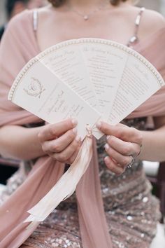 a close up of a person holding a fan with writing on the front and sides