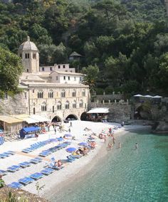 people are on the beach in front of an old building