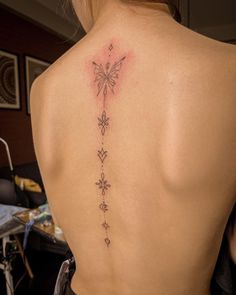 the back of a woman's neck with tattoos on her upper and lower back