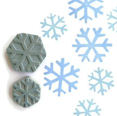 four snowflakes are shown on a white surface with blue and gray shapes in the background