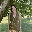 a woman standing under a tree in a green dress