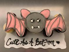 a cupcake decorated like a bat with the words cute as a bacon on it