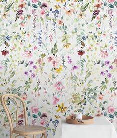 a white table and chair in front of a floral wallpaper with flowers on it