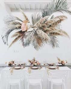 the table is set with white linens and place settings, along with palm trees