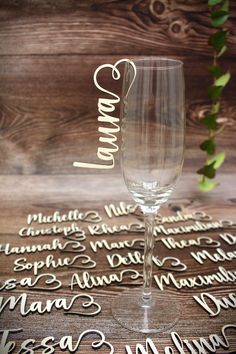 a wine glass sitting on top of a table next to a wooden sign with names