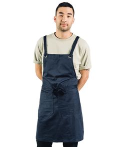 a man standing with his hands on his hips wearing an apron and looking at the camera