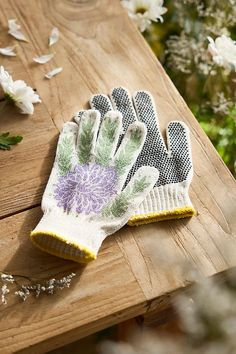 a pair of gardening gloves sitting on top of a wooden table next to white flowers