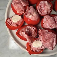 some sliced up tomatoes on a plate with cheese and meat in the middle, ready to be eaten