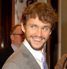 a man in a suit and tie smiling at the camera