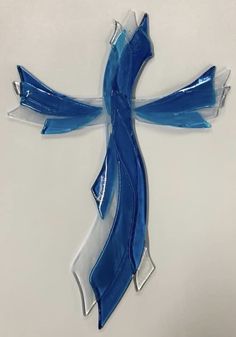 a blue and white glass cross hanging on a wall