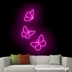 a living room with a white couch and purple neon butterflies on the wall above it