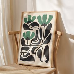 a framed art piece sitting on top of a wooden chair in front of a window