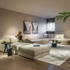 a woman sitting on top of a white couch in a living room next to a potted plant