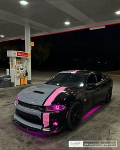 a black and pink dodge charger parked at a gas station with neon lights on it