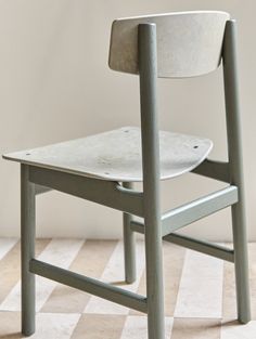 a white chair sitting on top of a checkered tile floor next to a wall