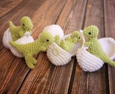 three crocheted baby ducks are sitting next to each other on a wooden surface