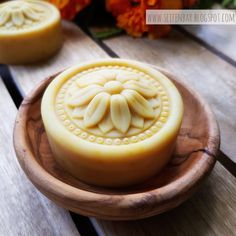 two soaps sitting on top of a wooden plate next to orange flowers and leaves