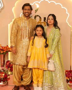 a man and two women standing next to each other in front of a flower display