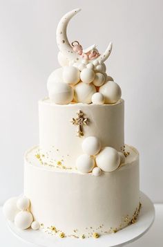 a three tiered cake with white frosting and gold sprinkles