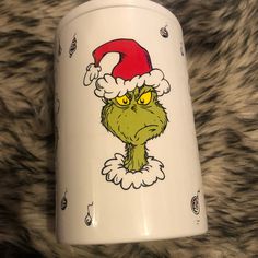 a white coffee mug with an image of the grin on it's face and red santa hat