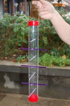 a person is holding up a tall tube with purple sticks sticking out of it's side