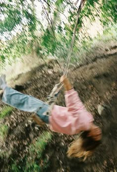 a person swinging on a rope in the woods