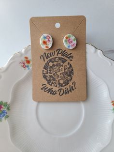 a pair of earrings with the words new plate no dish on it