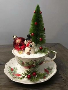 a teacup with christmas decorations on it and a small tree in the top one