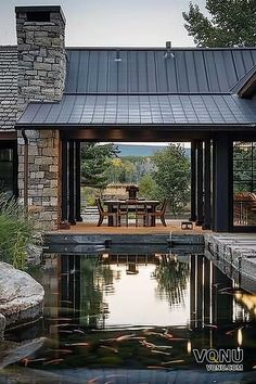 A beautiful modern rustic home featuring a seamless indoor-outdoor living space with natural stone, metal roofing, and a serene pond reflecting the surrounding landscape. Wyoming Mountains, Outdoor Dining Room, Rustic Contemporary, Mountain Retreat, 인테리어 디자인, Rustic Style, Future House, Wyoming, A House