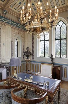 an ornately decorated room with chandelier and table in the center surrounded by chairs