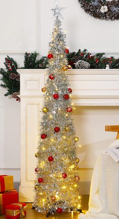 a white christmas tree with red and gold ornaments in front of a fireplace mantel