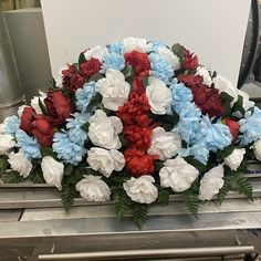 red, white and blue flowers are arranged in a bouquet on a conveyor belt