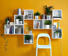 a white chair sitting in front of a wall filled with potted plants and books