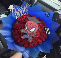 a bouquet of red roses in the shape of a spider - man on top of a car dashboard