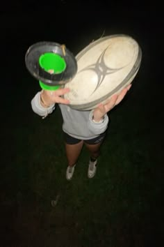 a person holding a green and white frisbee in their hands at night time