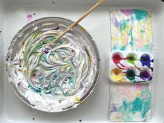 a plate with paint and a brush on it next to a paper towel that has been painted