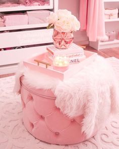 a pink ottoman with flowers and candles on top