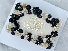 a birthday cake with white frosting and black flowers on it's side, sitting on top of a card that says happy birthday