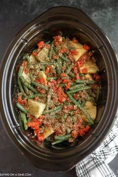 a crock pot filled with green beans and red peppers, topped with seasoning