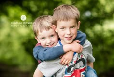 two young boys hugging each other in the park