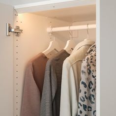 an open closet with clothes hanging on hooks