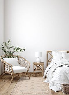 a bedroom with white walls and wooden flooring is pictured in this image, there are two wicker chairs next to the bed